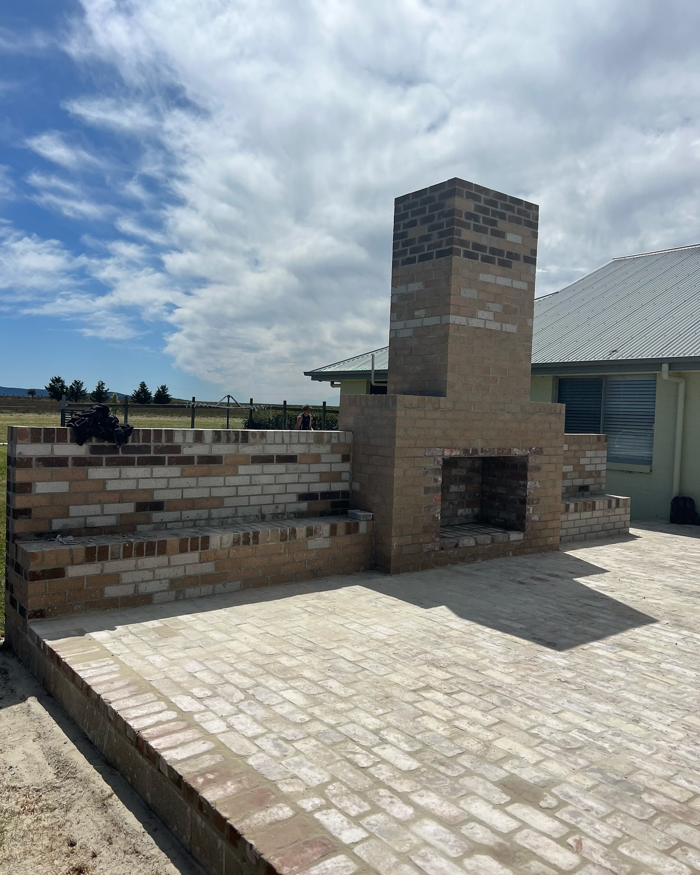 Outdoor brick fireplace and paved courtyard shared by Whittaker Bricklaying Services